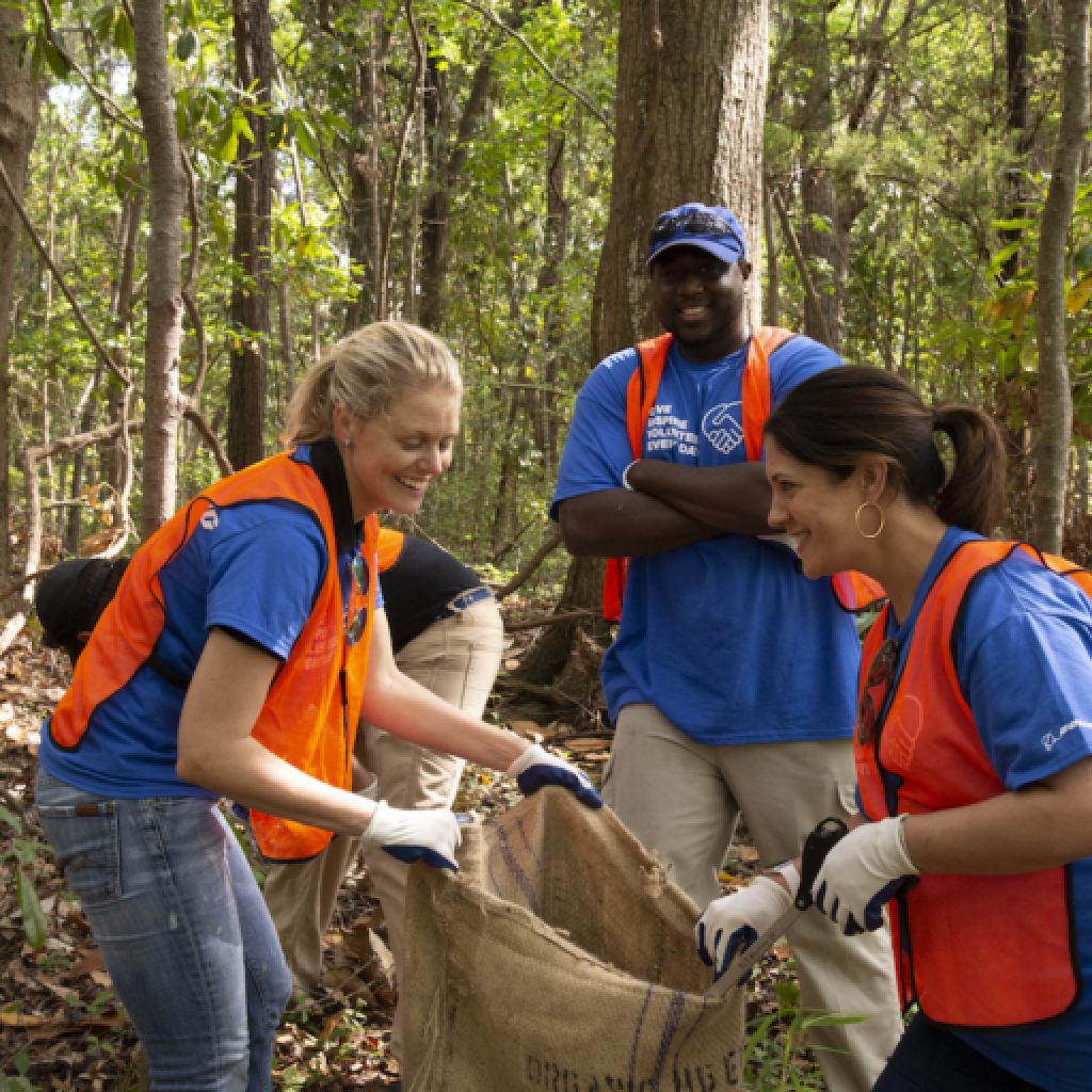 This image shows three people picking up litter in a forest environment 